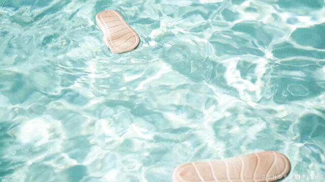 Pink flip flops floating in turquoise pool water