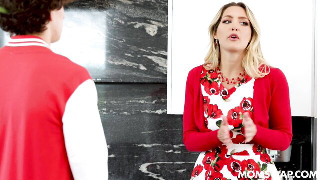 Blonde MILF in red floral dress talks to young guy in varsity jacket - Mom Swap lesson