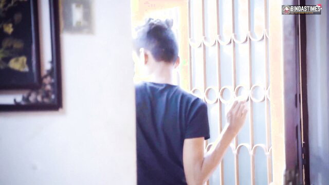 Asian man in tight black tee at window, wife sharing tease