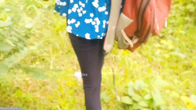 Indian girl in blue top and tight pants walks with backpack in wild outdoors