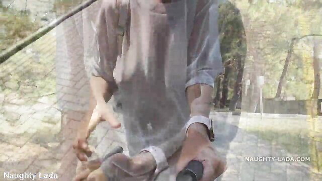 Asian beauty in sheer transparent dress teases with selfie stick outdoors