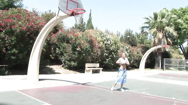 Ebony guy in speedo poses on basketball court in wet wild outdoor scene