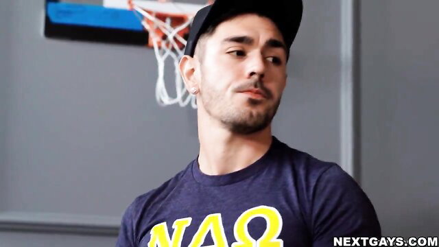 Hot Latino guy in black cap and NAGA tee poses sexy near basketball hoop