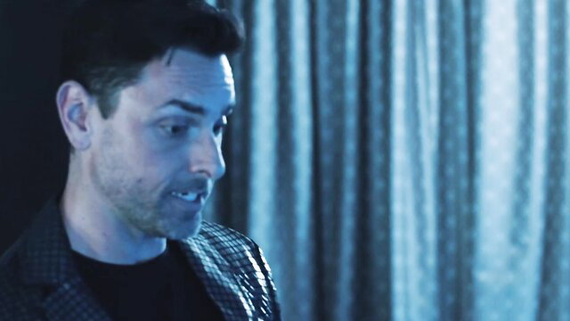 Alex Jones smirks intensely in dark leather jacket, blue lighting