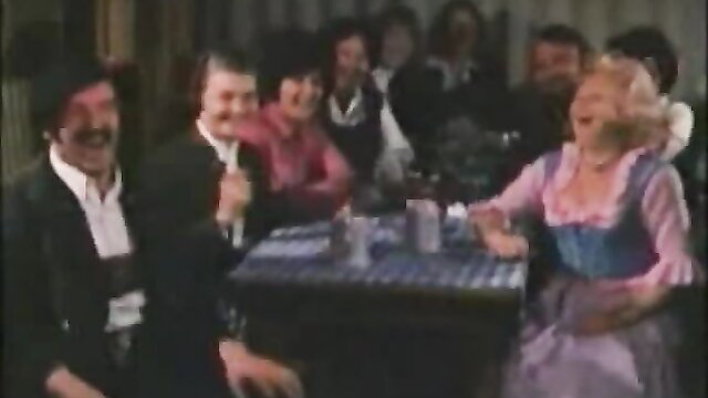 Retro MILF in dirndl laughs with suited men at table in vintage scene