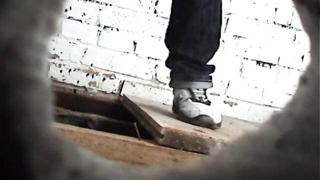 Man's foot in jeans and sneakers steps over hole in restroom floor voyeur cam