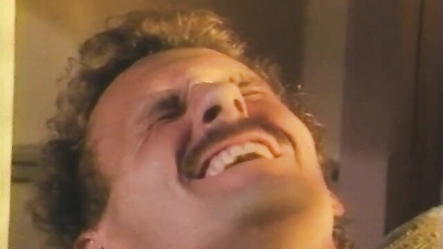 Hairy guy with curly hair laughing wildly at adult party