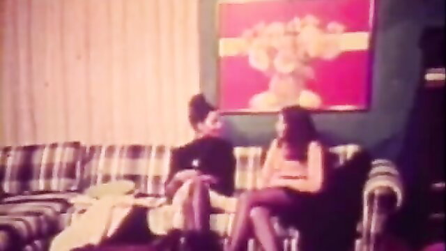 Retro couple on sofa, woman in fishnets seduces for titty fuck