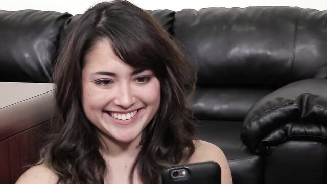 Smiling brunette Latina babe on Backroom Casting Couch holds phone