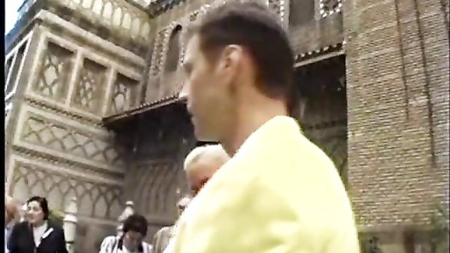 Classic Evil Angel scene: man in yellow jacket outside ornate building