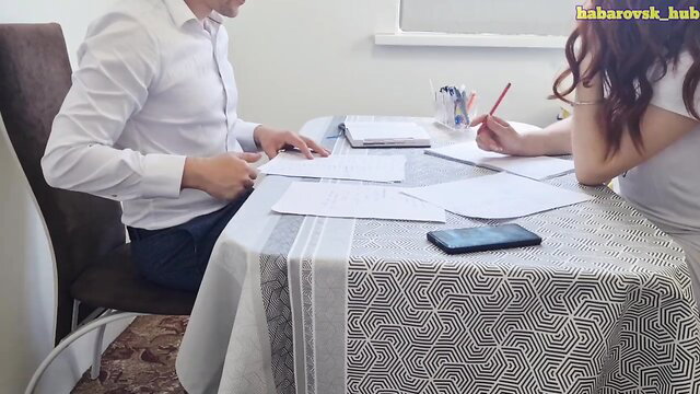 Redhead student in white top reviews papers with man at table
