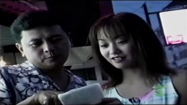 Japanese AV babe with bangs smiles at Thai guy in Hawaiian shirt holding phone