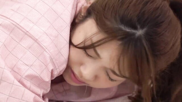 Asian JAV girl with bangs rests head on man's pink checkered shirt in aphrodisiac sex embrace