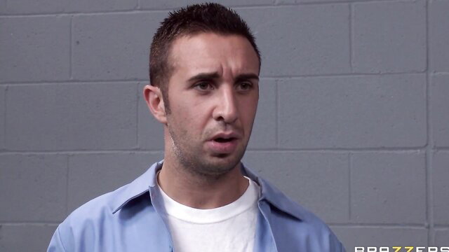 Prisoner man in blue uniform stares shocked in jail cell