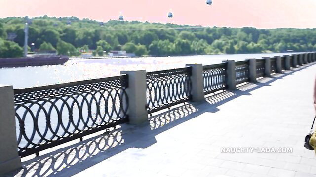 Blonde wife teases with big tits in sexy dress on sunny riverside bridge