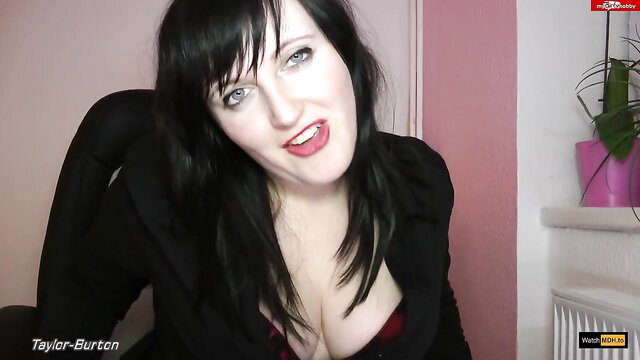 Taylor Burton in black blazer with deep cleavage, smirking seductively