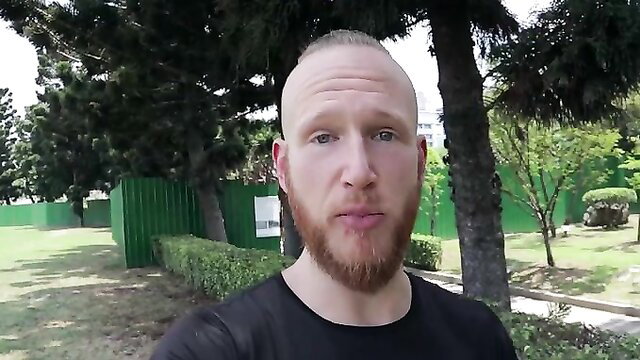 Bald bearded white guy in black tee at swinger hotel outdoors