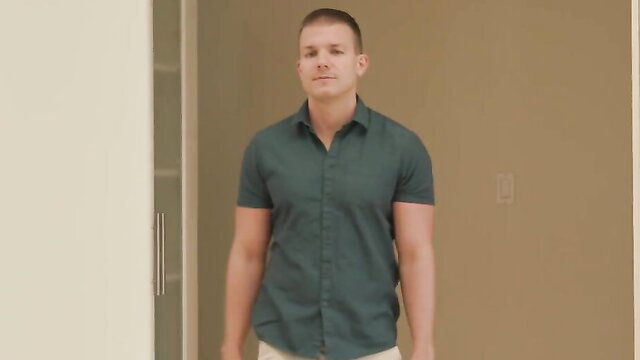 Handsome muscular stepson in green shirt and shorts stands smiling