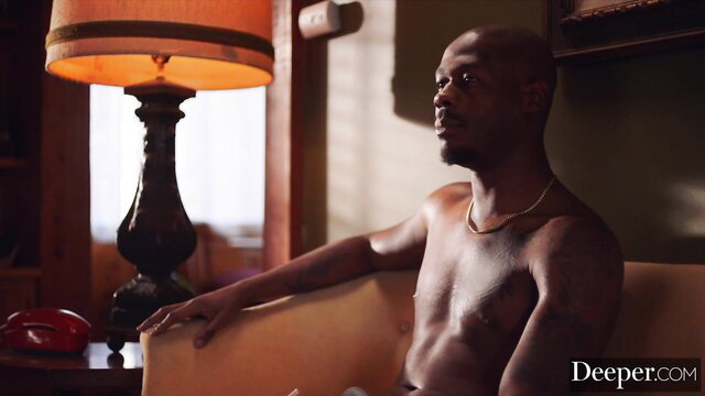 Shirtless muscular black man with tattoos lounges nude in Deeper video