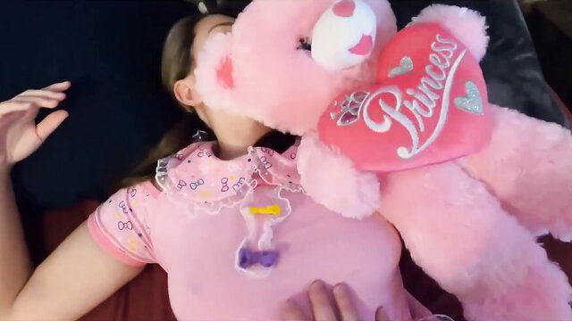 Cute stepdaughter in pink princess onesie cuddles teddy bear