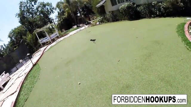 Sunny backyard putting green with palm trees and forbiddenhookups watermark