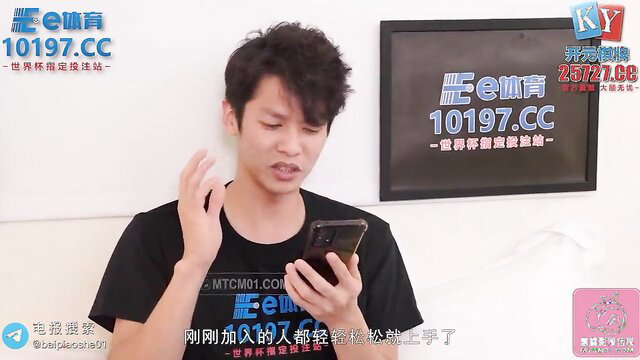 Asian guy in black tee holds phone, seductive pose in Peach Media adult video thumbnail