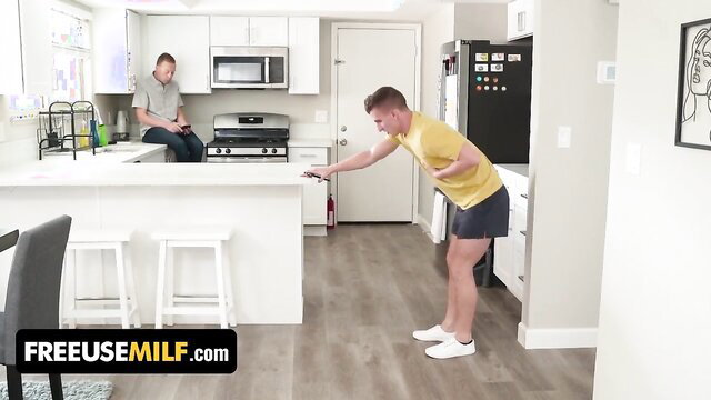 Crystal Clark in yellow tank top and shorts bends over kitchen counter