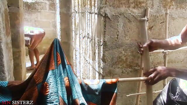 Ebony woman in colorful wrap bathing near man with bamboo in outdoor bathroom