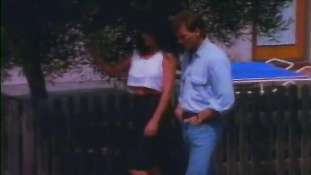 Retro couple outdoors: busty brunette in crop top skirt with man in shirt jeans