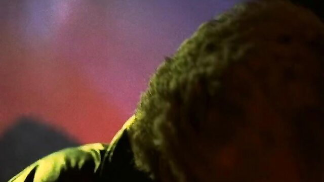 Blurry closeup of black man's curly green-tinted hair in psychedelic red-purple porno glow