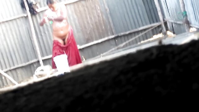 Indian man in red lungi outdoors with bucket, amateur tease