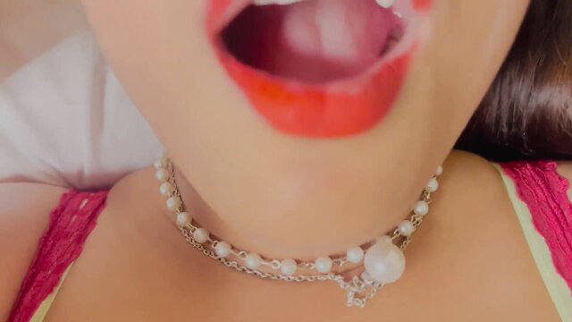 Asian woman with pearl necklace opens wide red lips in steamy closeup