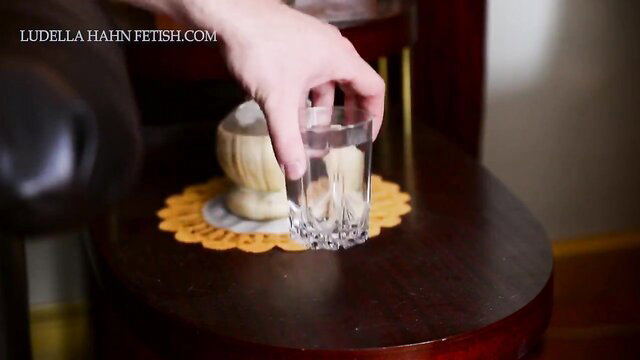Ludella Hahn holds glass in hypnotic redhead mind-control fetish scene