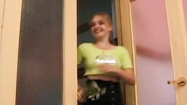 Blonde teen in neon green crop top and black skirt at open door