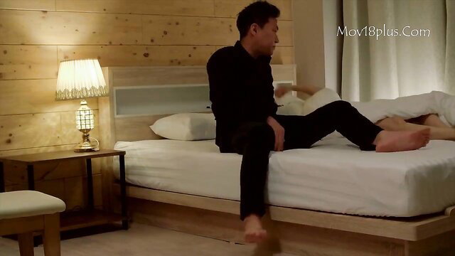 Asian man in black shirt pants sits on bed in JAV bedroom scene