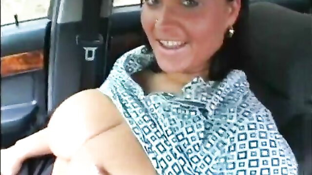 Busty MILF smiling in car, shawl slipping off huge tits