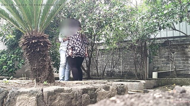 Indian stepsis in printed top & jeans hugs stepson in lush outdoor garden