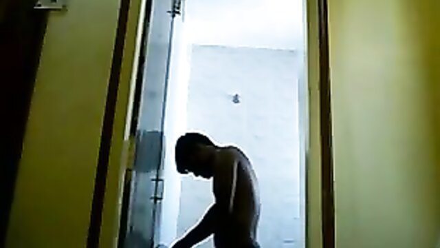 Shirtless Asian man crouching nude in bathroom doorway