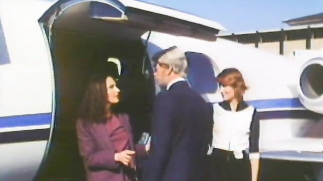 Retro 1979 Satin Suites women greet suited man at plane door