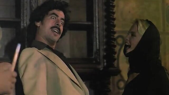 Classic VCX porn scene: man in suit laughing with big-titted blonde in hood