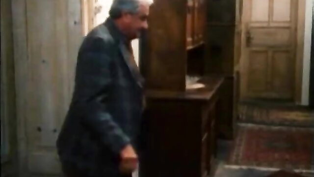 Mature man in suit hides behind desk in classic erotic scene