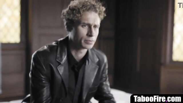 Young curly-haired reporter in leather jacket faces psycho guy intensely