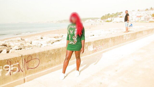 Hot ebony babe in green mini dress poses on beach promenade