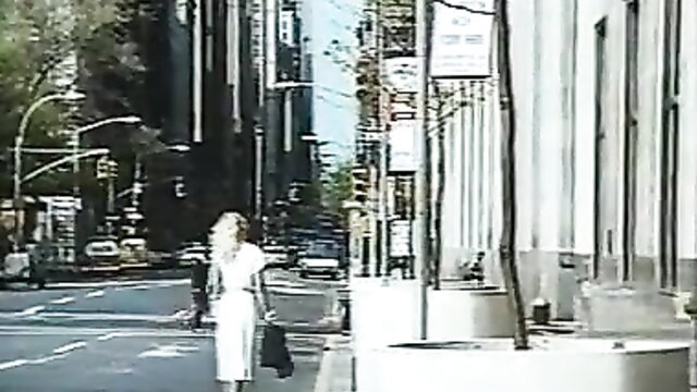 Blonde MILF in tight white dress walking NYC street, frisky tease