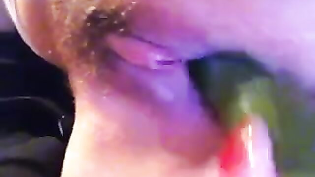 Closeup of woman with hairy pussy penetrated by cucumber in solo play