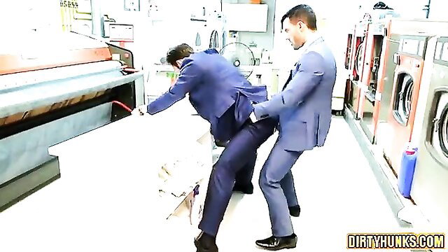 Two suited muscular men fucking in laundromat, one bent over ironing machine