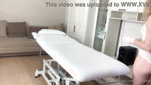 SugarNadya in white lingerie by massage table, sexy pose