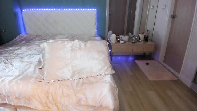 Minerva777 in luxurious white bed with blue LED lights, elegant bedroom