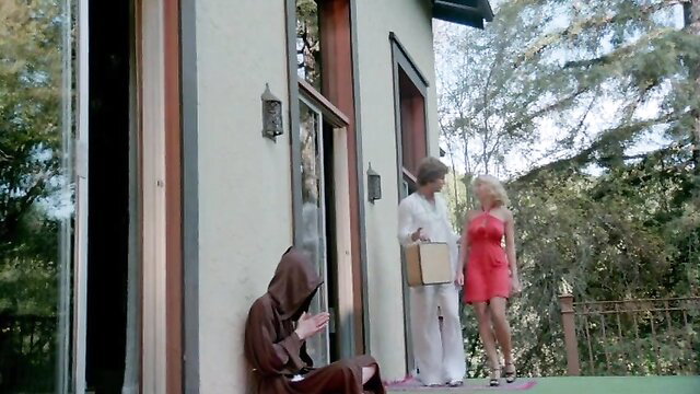 Erotic Adventures of Candy 1978: Blonde in red dress with man on porch by hooded friar