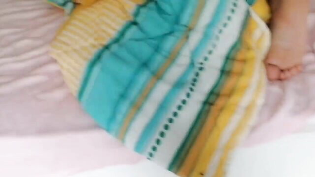 Amateur wife in colorful blanket on bed showing bare foot